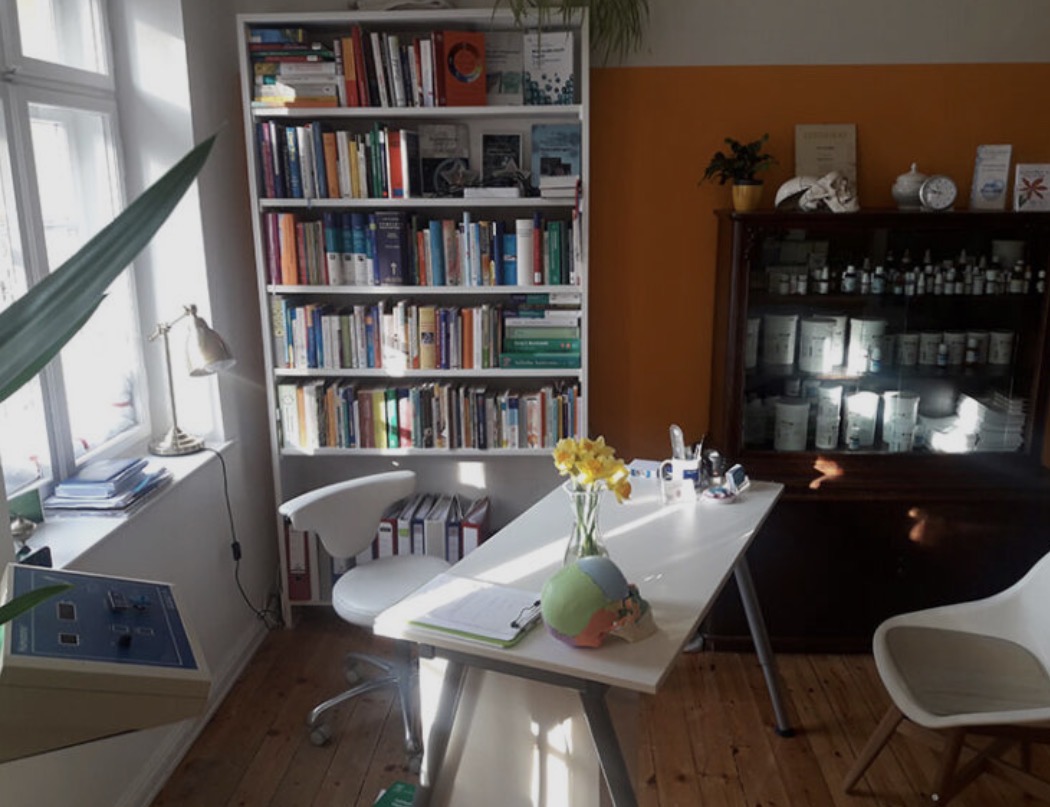 Sprechecke der ersten Praxis mit Fachbibliothek und Schreibtisch